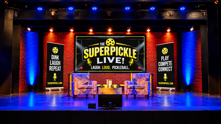 The Super Pickle Live stage with yellow and white branding, red brick walls, and blue stage lights